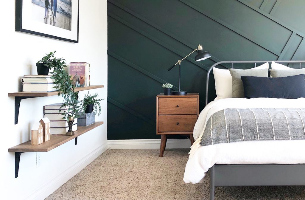A bedroom with a green feature wall and a bed.