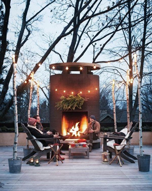 A group of people sitting around a fire pit in a winter garden.