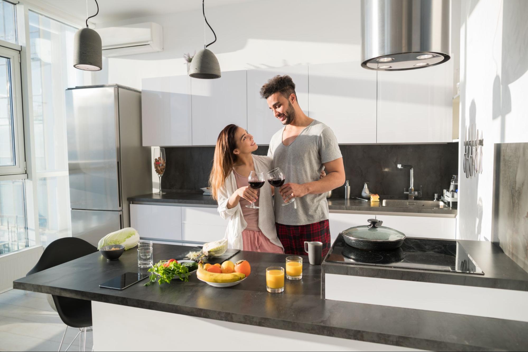 A young couple using kitchen appliances in a modern kitchen.