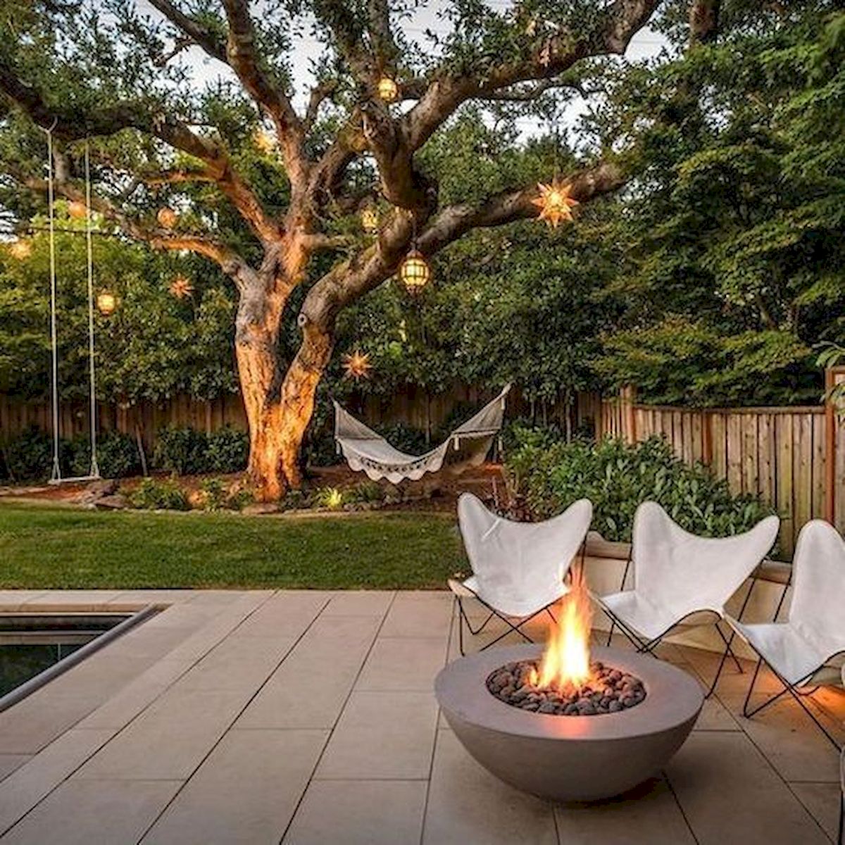 A garden with a fire pit and a tree.