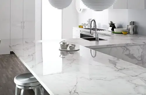 A modern kitchen with white marble counter tops and material imitations.