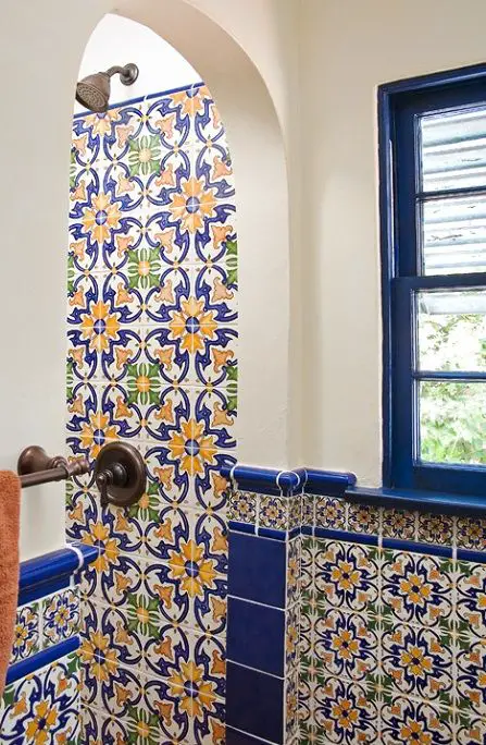 A Spanish-inspired bathroom with blue and yellow tiles and an arched window.