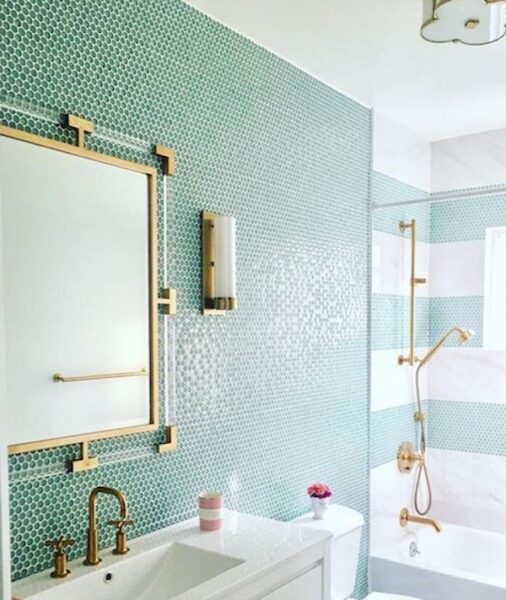 Bathroom renovation with green tile and gold accents.