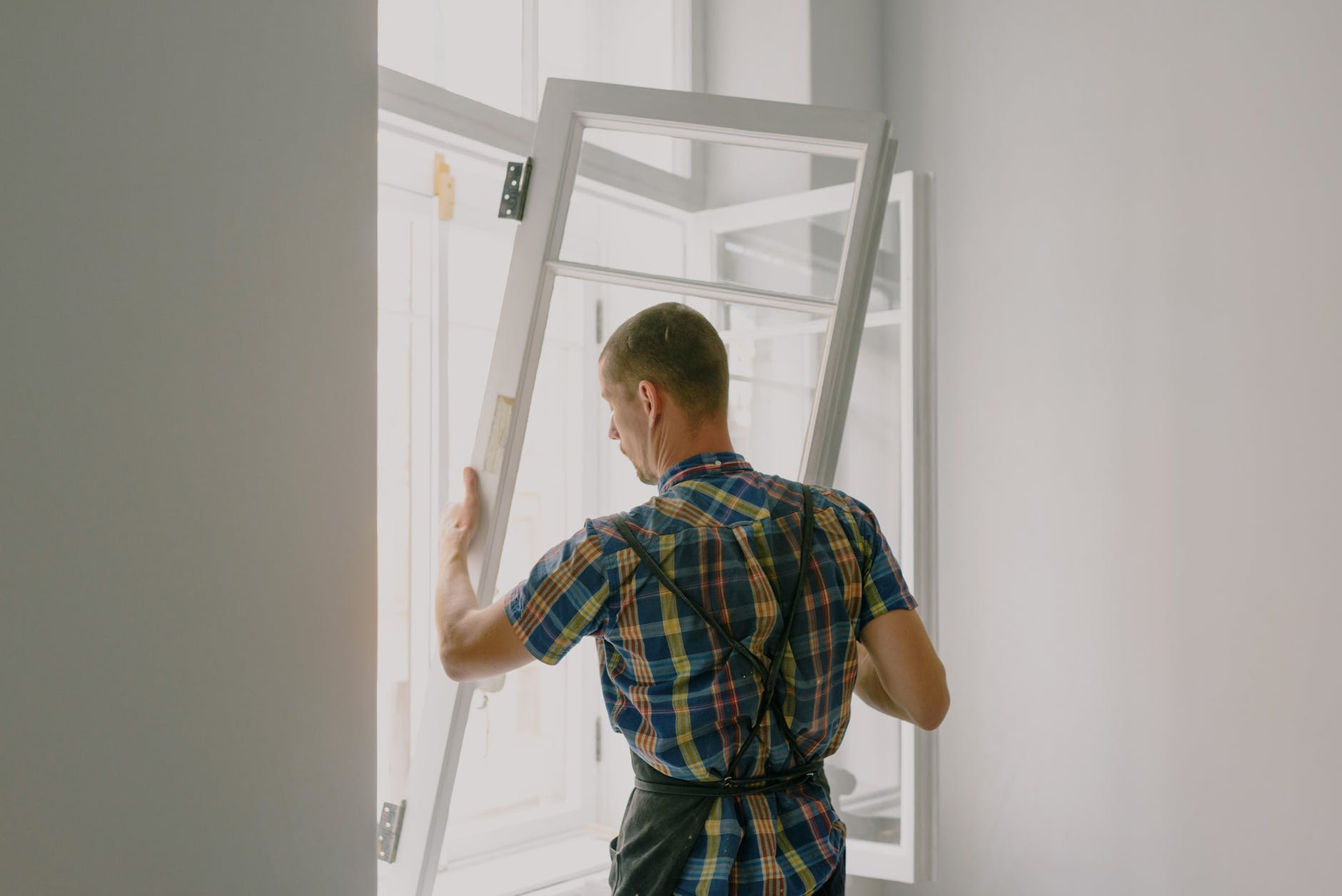 A man renovating a window frame in a room.