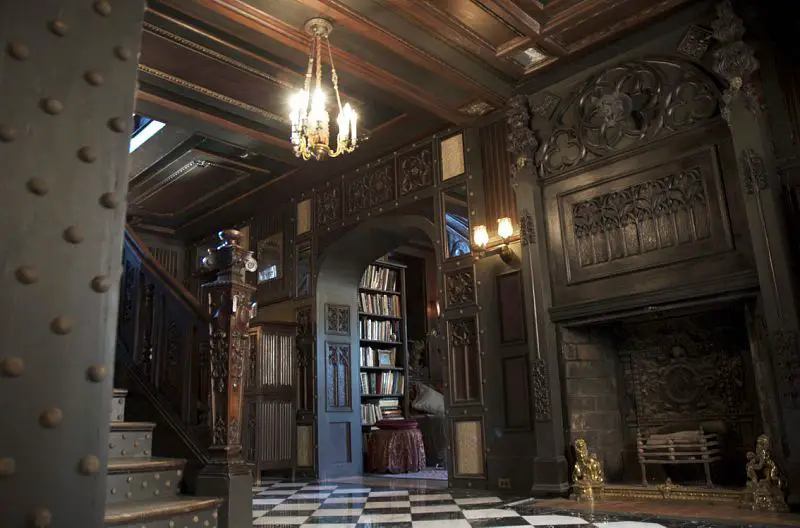 An ornate Victorian Gothic-inspired room with a fireplace and a checkered floor.