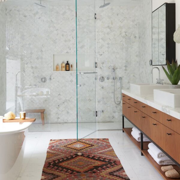 A bathroom designed with a glass shower and rug.