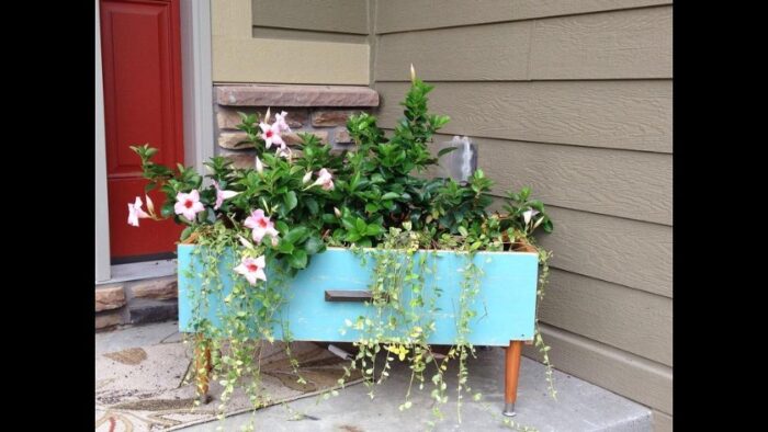 A recycled blue planter with flowers in a garden.