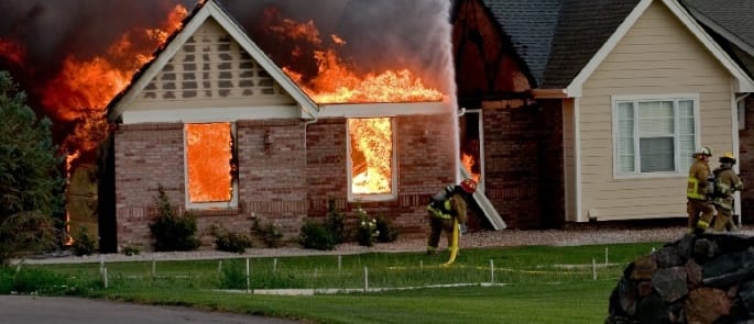 A firefighter is battling a fire at a house, demonstrating home fire preparedness.