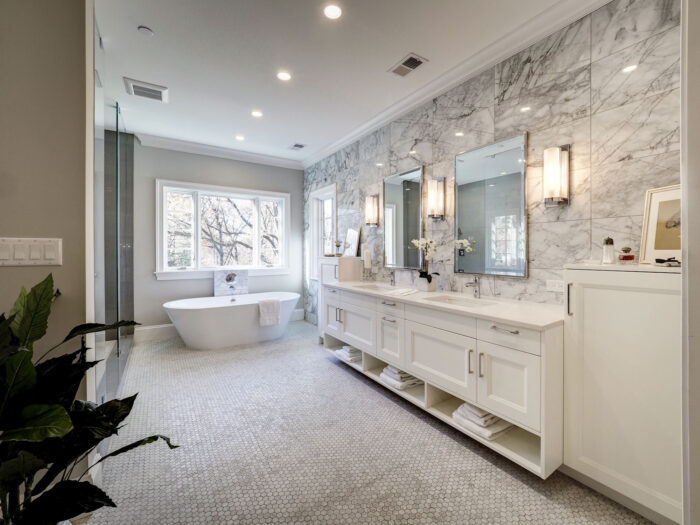 A bathroom with marble counter tops and a tub, designed in white.