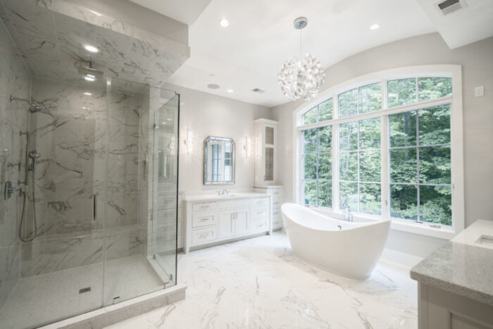 A white bathroom design with a large tub and a chandelier.