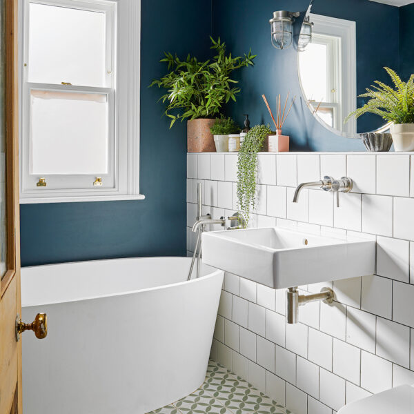 A bathroom with a modern design featuring blue walls and a white tub.