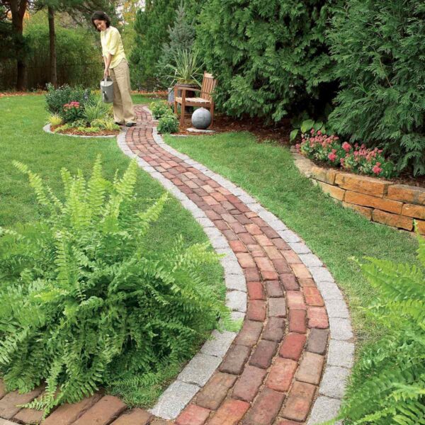 A woman is walking down a recycled path in a garden.