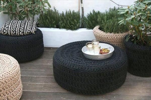 Black and white recycled crocheted ottomans on a wooden deck in a garden.