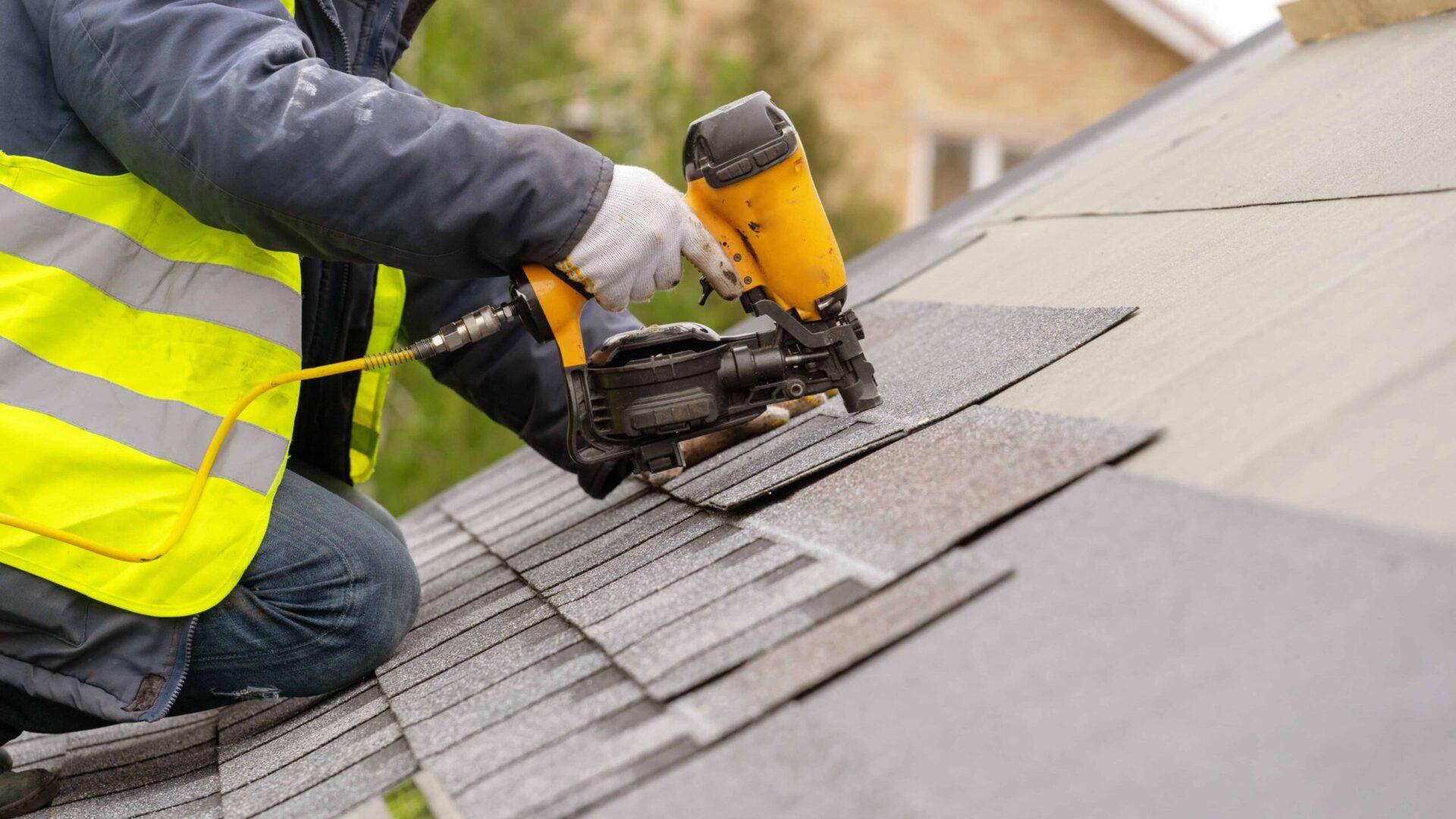 A man is working on a shingled roof for roof repair services.
