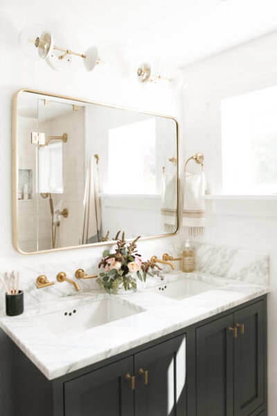 A black and gold bathroom with a gold mirror showcasing elegant bathroom design.