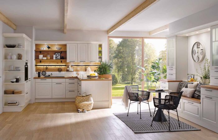 An open kitchen style with a white theme and wooden floors.