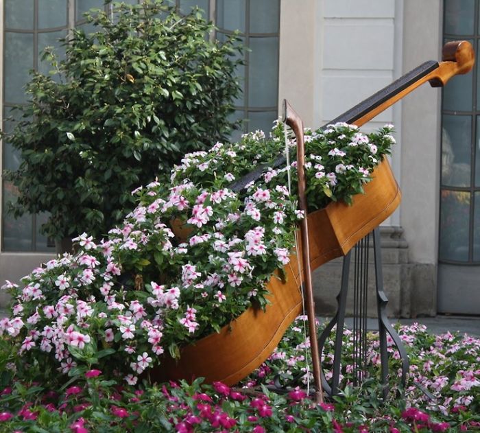 A recycled violin made out of flowers in a garden.