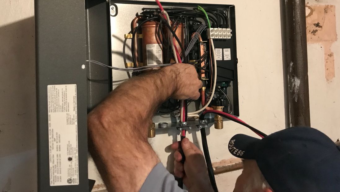 A man is electrifying a hot water heater.