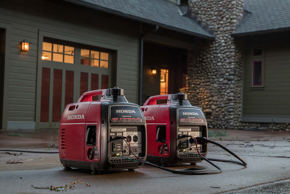 Two honda generators providing portable power in front of a house.