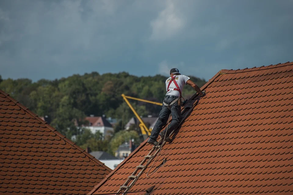 A man performing roofing restoration on a ladder.