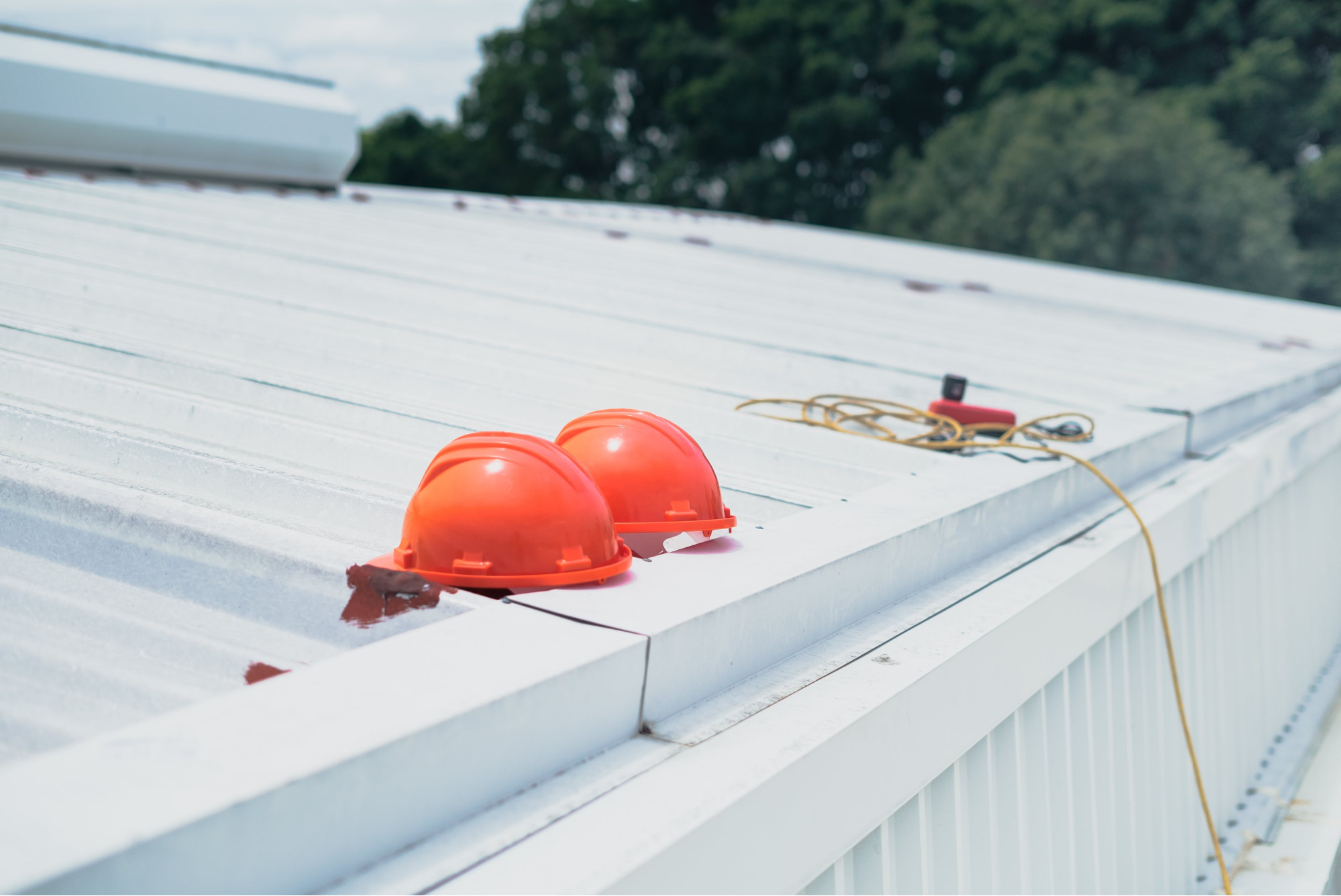 Two orange hard hats on the roof of a building being inspected by Gutter Experts.