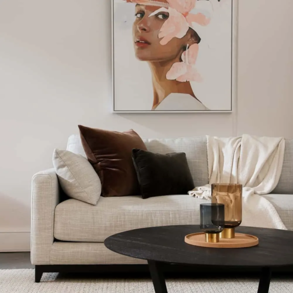 A painting of a woman in a pink hat hangs above a coffee table.