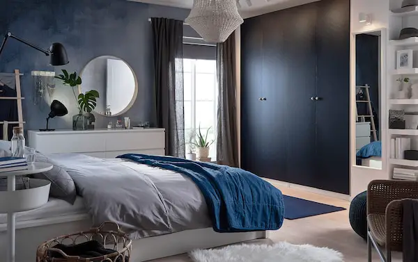 A bedroom with modern blue walls and white furniture.