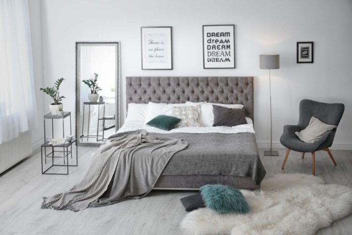 A modern bedroom with a grey bed and a grey rug.