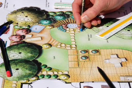A person sketching a garden design for a landscaping project.