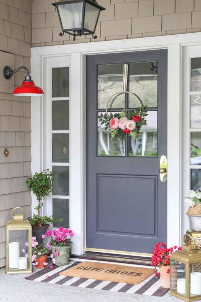 Front door decorated with flowers, lantern, front porch