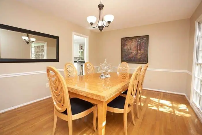 A dining room with a wooden table and chairs and a mirror.