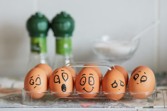 A tray of eggs with faces drawn on them for a fun home decoration.