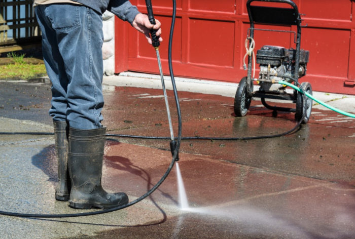 A man is pressure cleaning his driveway.