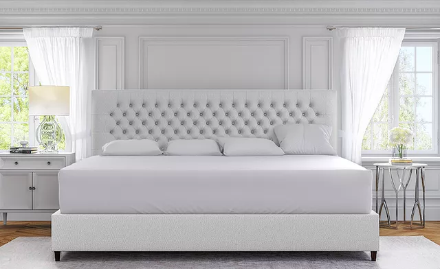 A white king bed with tufted headboard in a bedroom.