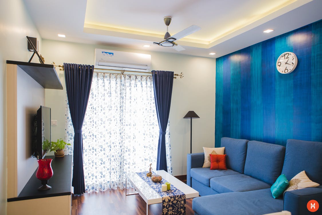 A living room with blue walls and a blue couch, decorated beautifully.