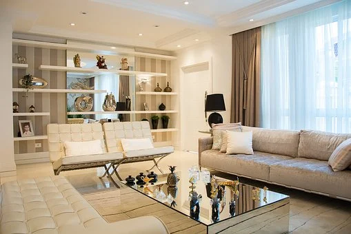 A furnished living room with white furniture and a glass coffee table.