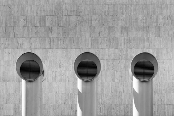 Black and white photo of three HVAC system air conditioners in front of a wall.