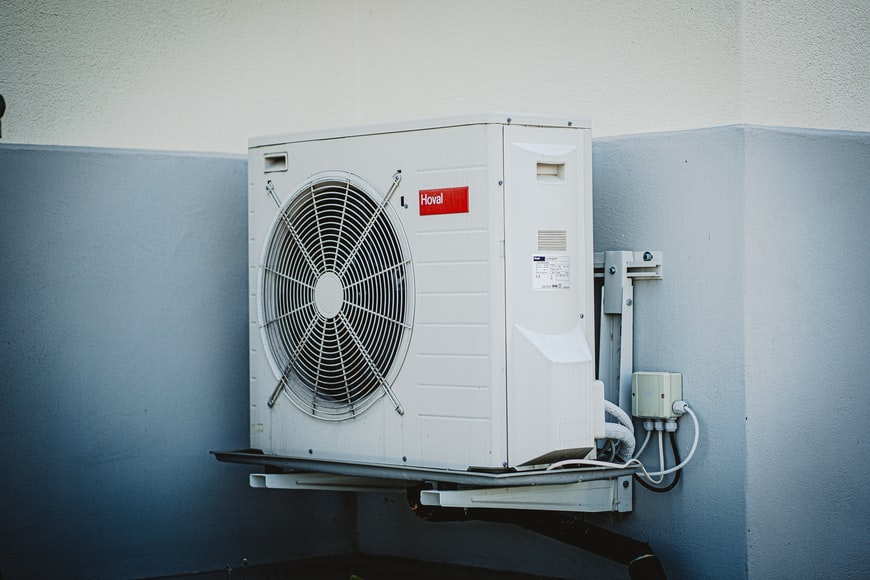 An AC fan motor attached to the side of a building.