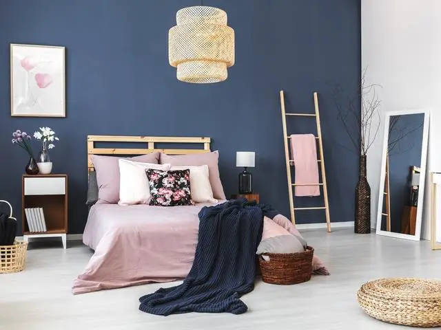 A bedroom with blue walls and a pink bed.