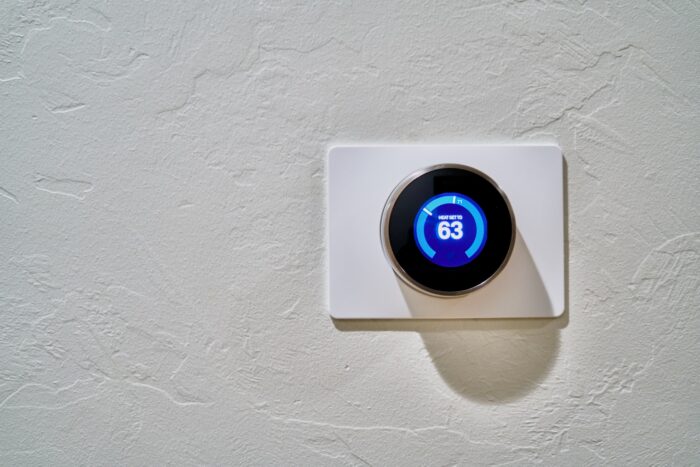 A smart thermostat controls HVAC systems and is displayed on a wall.