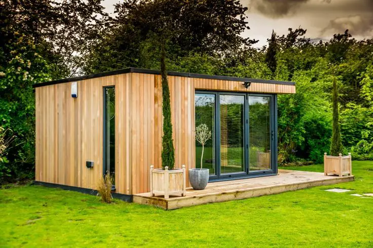 A garden shed in the middle of a grassy area.