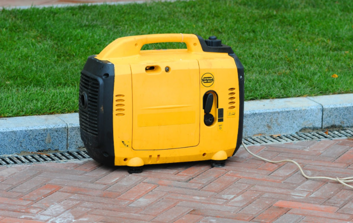 A portable suitcase generator sitting on a brick walkway.