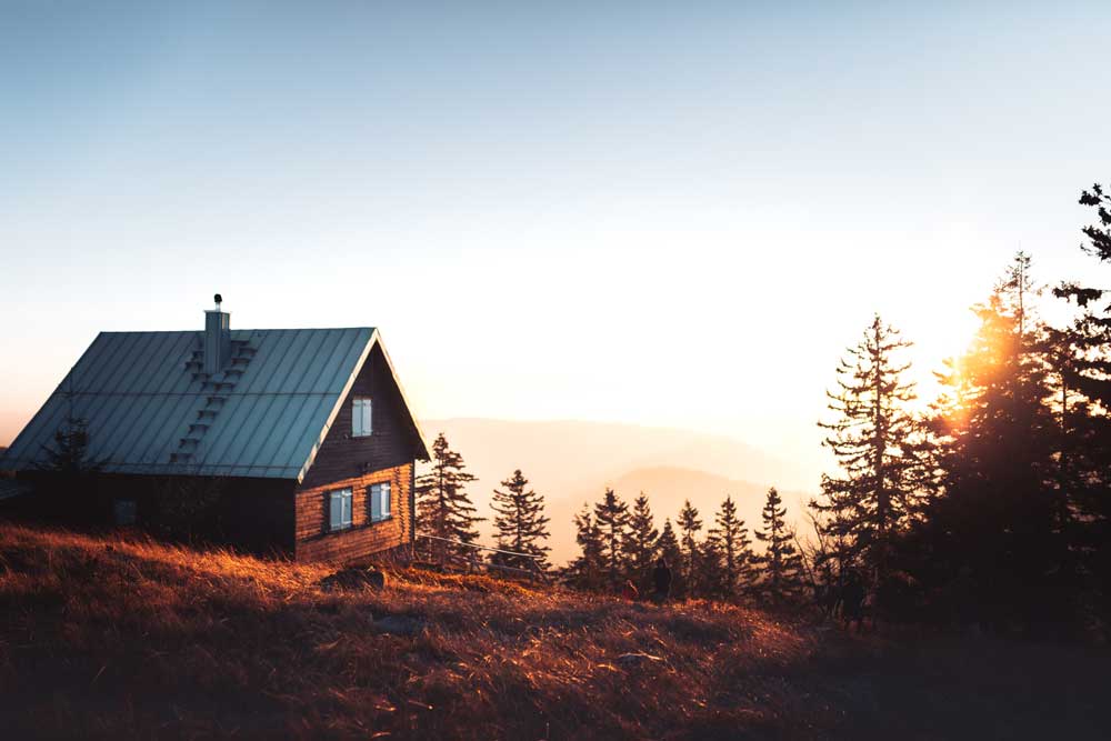 A vacation home cabin sits on top of a hill at sunset.