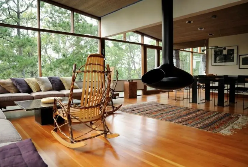 A living room with large windows and a rocking chair.