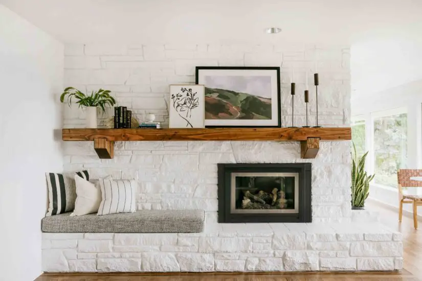 A living room with a white brick fireplace and a bench.