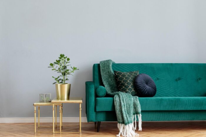 A green velvet sofa in a home with gold accents, ready to sell.