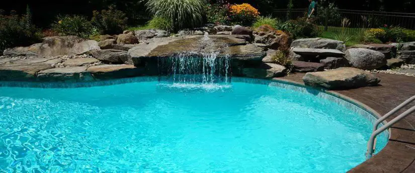 A swimming pool with a waterfall and rocks.