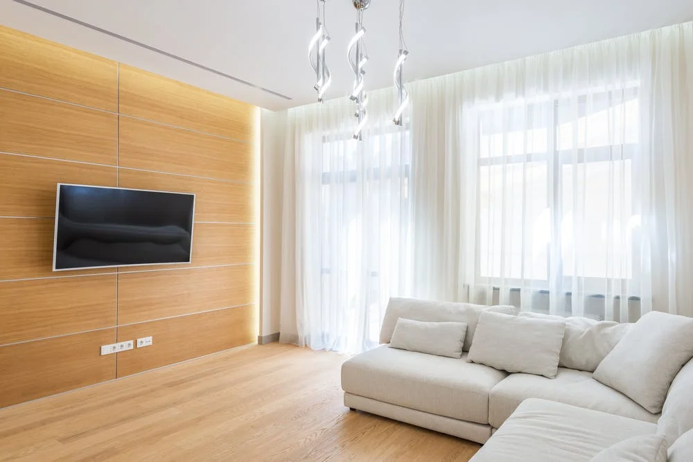 A white living room with wooden walls and a wall-mounted TV.