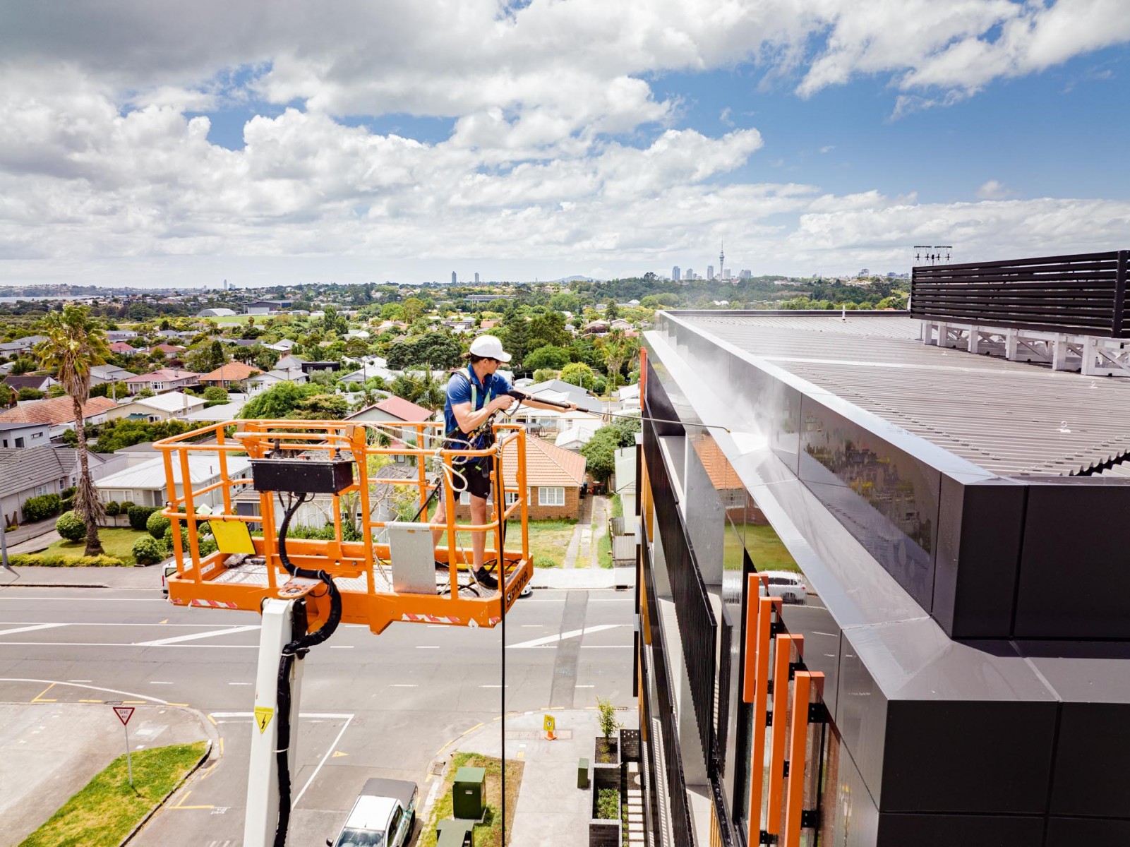 A man on a lift making your home or office look sparkling by cleaning the roof of a building.