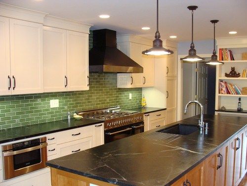 A kitchen with black counter tops and a soapstone backsplash.